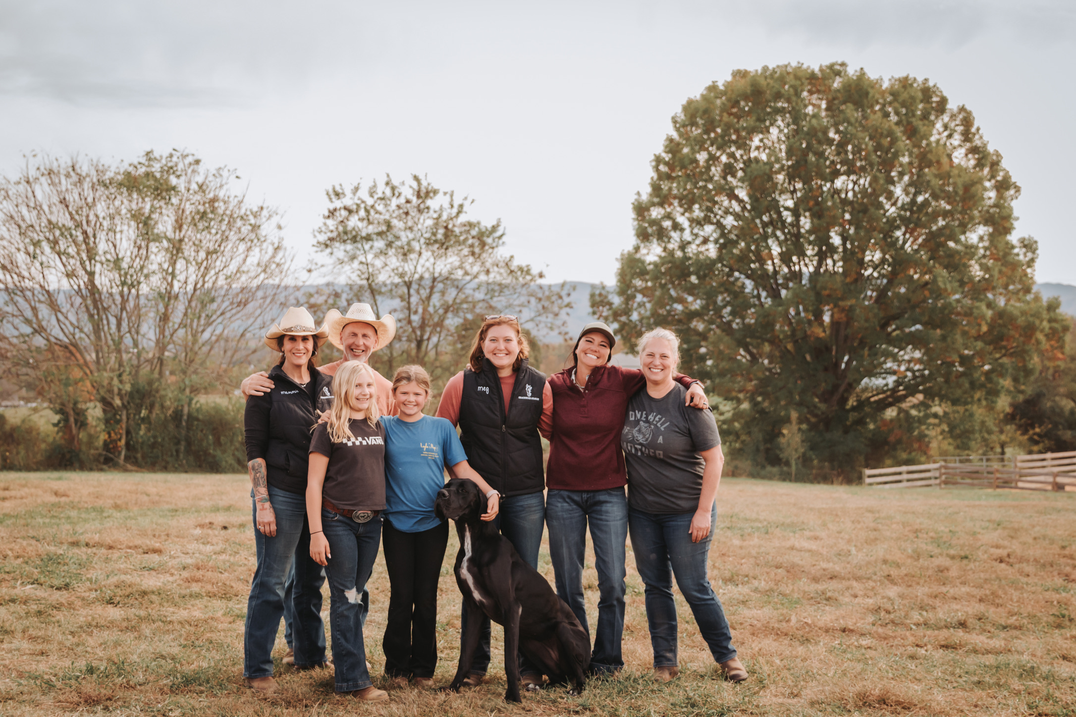 The Gracewood Acres family and crew together in the pasture with their Great Dane, mountains behind