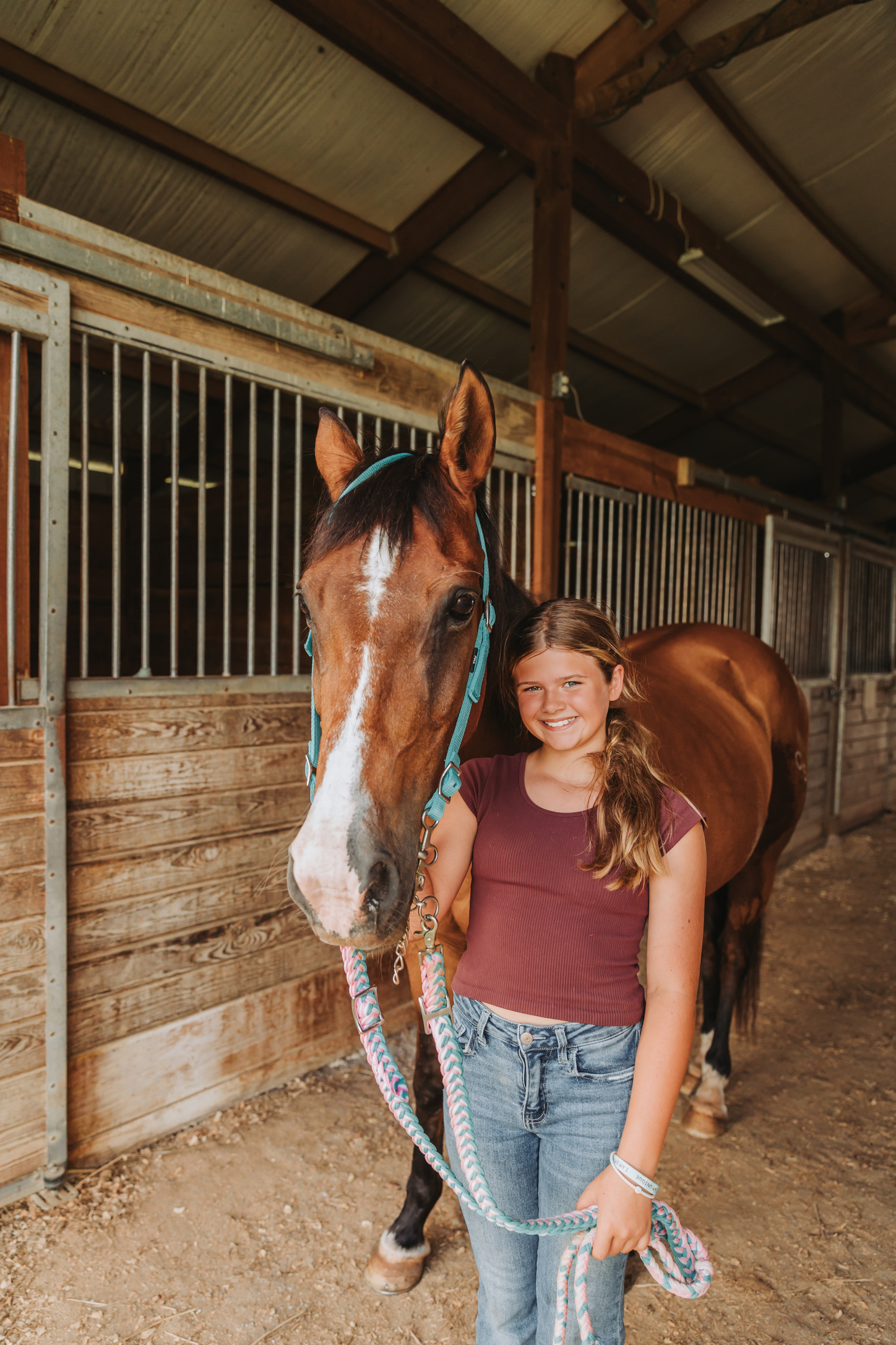 A young rider with a bay horse in the barn aisle