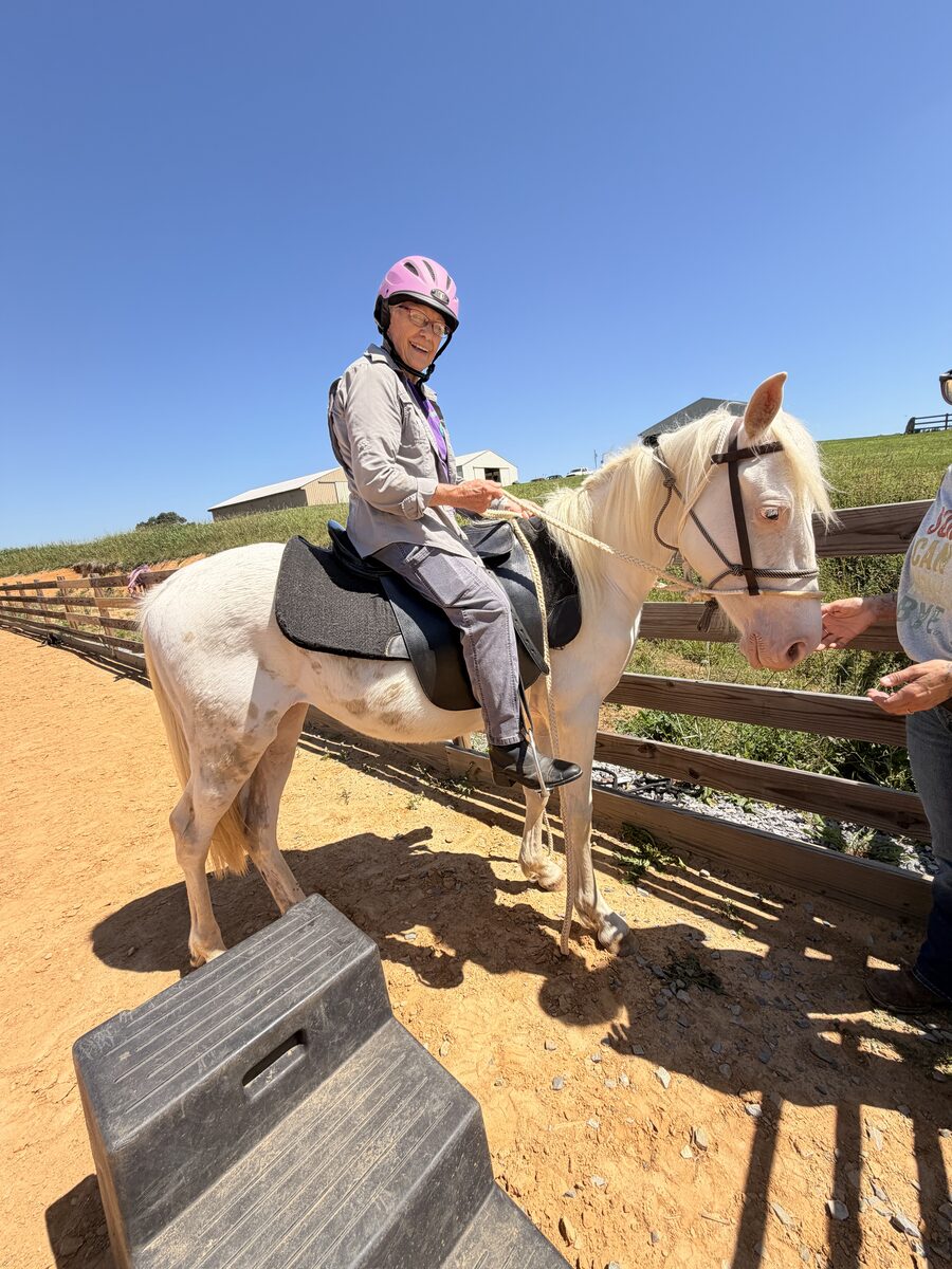 A young rider getting a leg up onto a palomino from the mounting block at Gracewood Acres