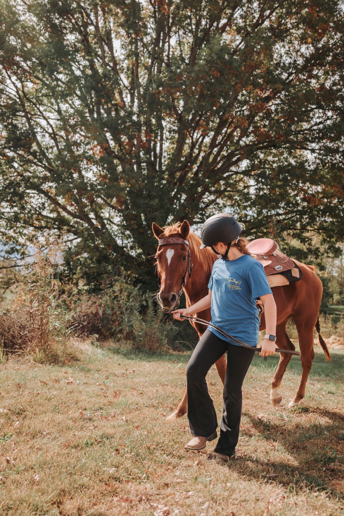 A young rider leading her horse in from the field